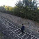 Kid lays down under a moving train